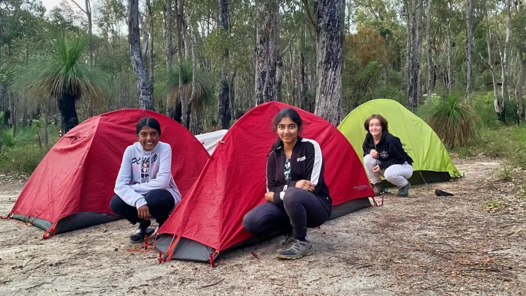 Three teen girls in front of their tents during a three day hike with LifeTrail