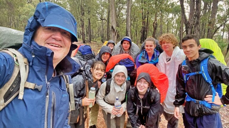 Didier from LifeTrail and group of teens posing for a photo in the rain and loving it