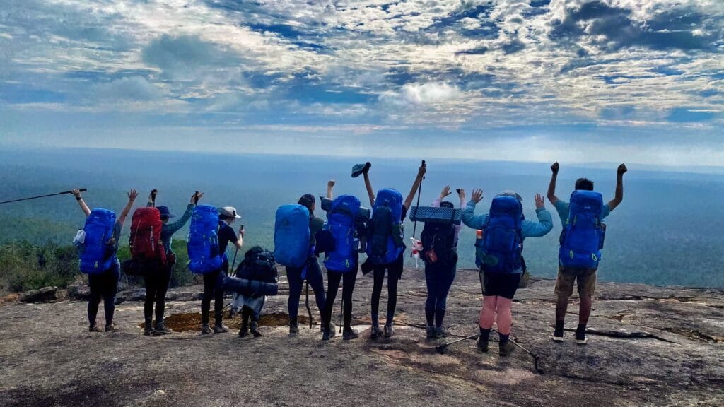 teens celebrating their climb with their arms up in the air