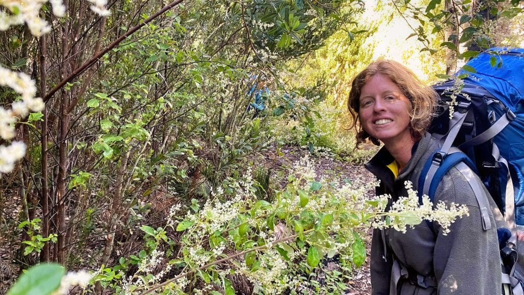 lady hiker posing with backpack and native flowers