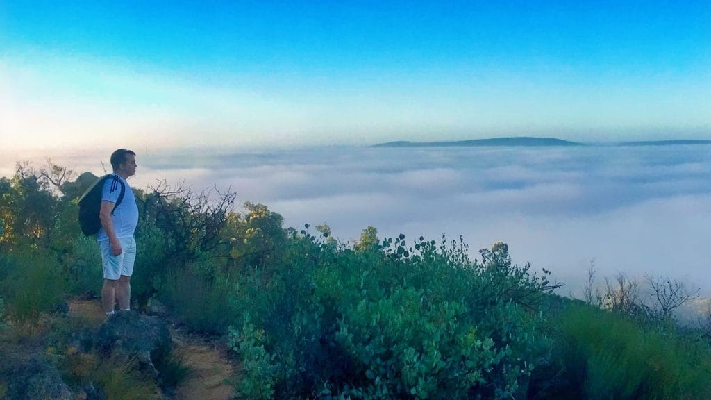 man overlooking low clouds during a hike