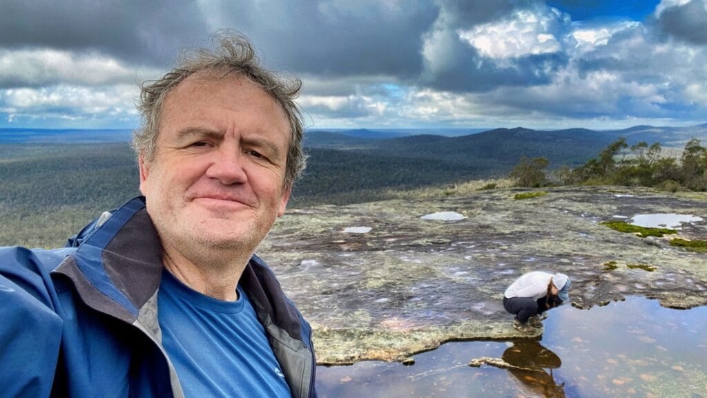 Man and woman on rock overlooking forest