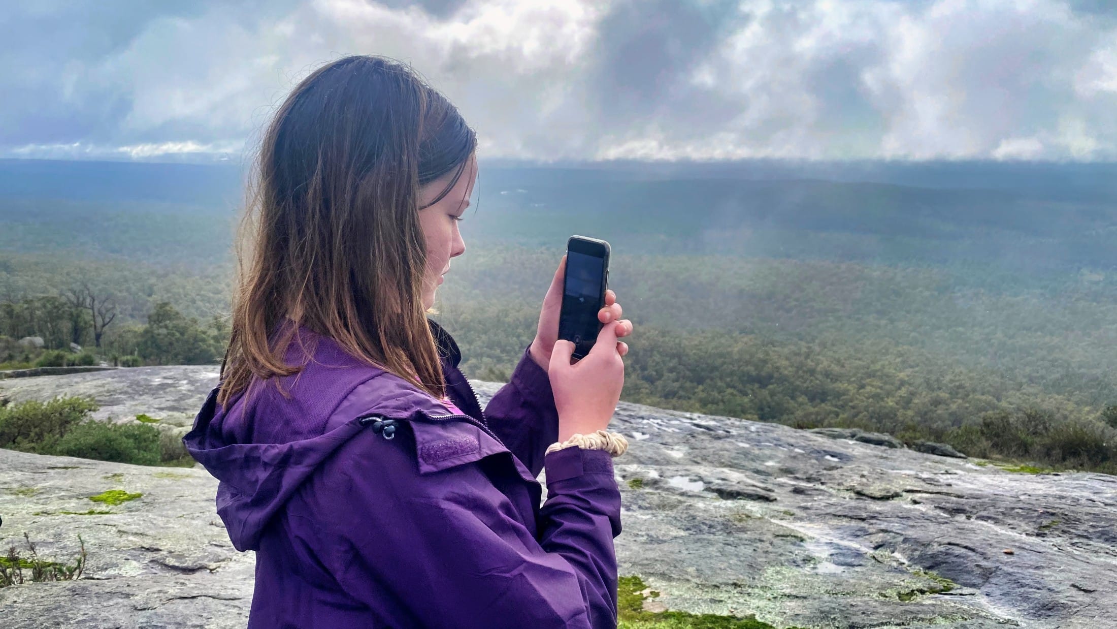 teen girl on her mobile on a rock