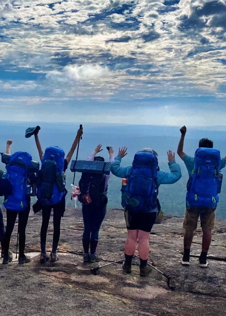 group of teen hikers celebrating with a view
