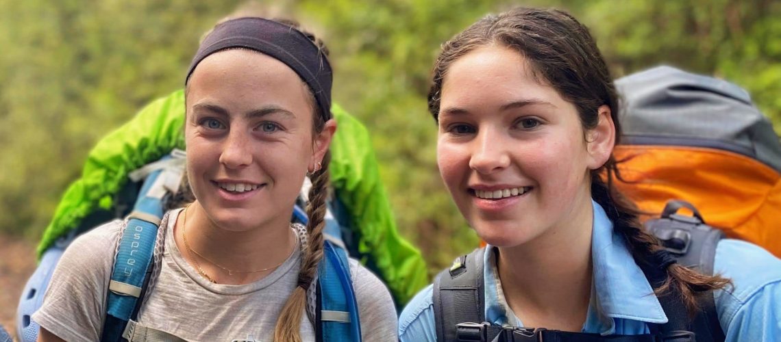 two smiling teen girls during a 7 day hike carrying their large backpacks